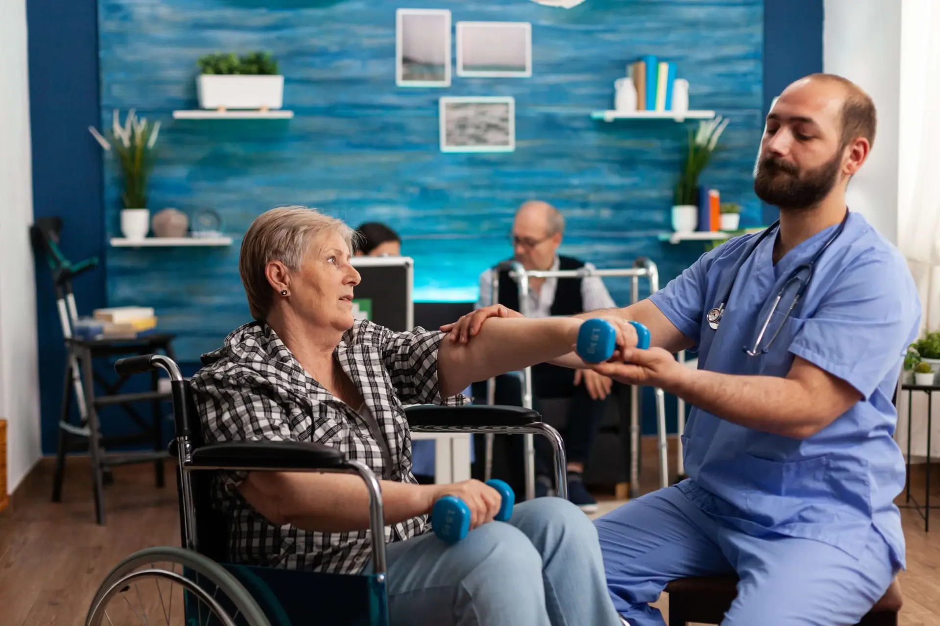 male-nurse-helping-senior-retired-disabled-woman-wheelchair-rehabilitate-using-dumbbels (1) (1)